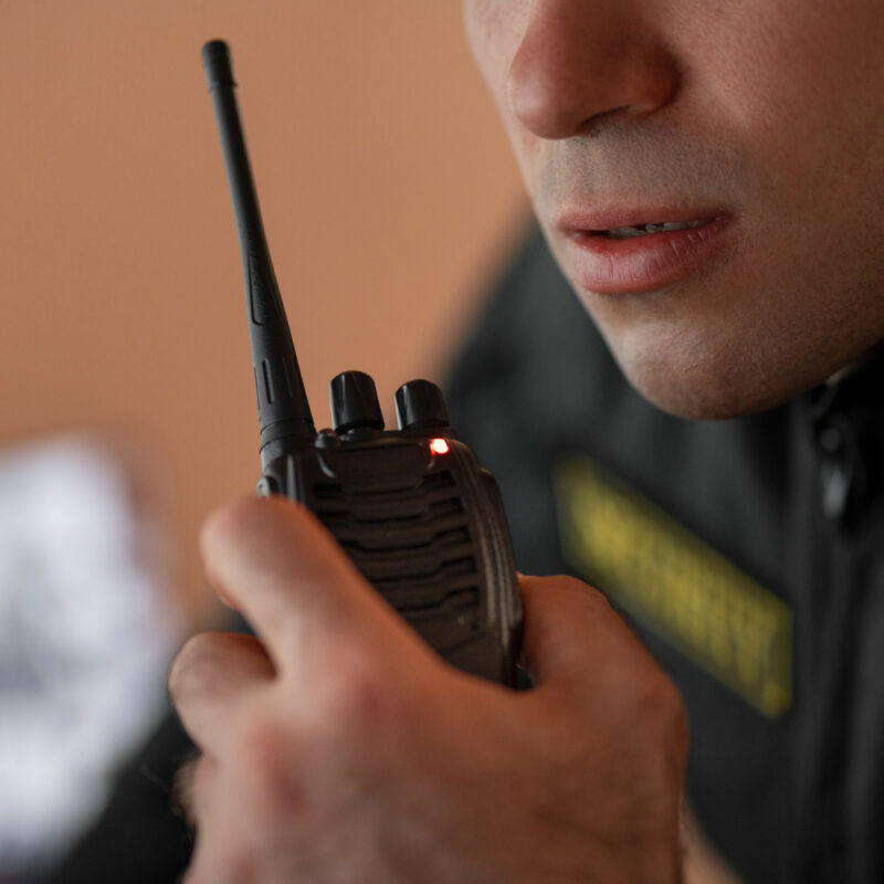 Portrait of male security guard with radio station and camera screens