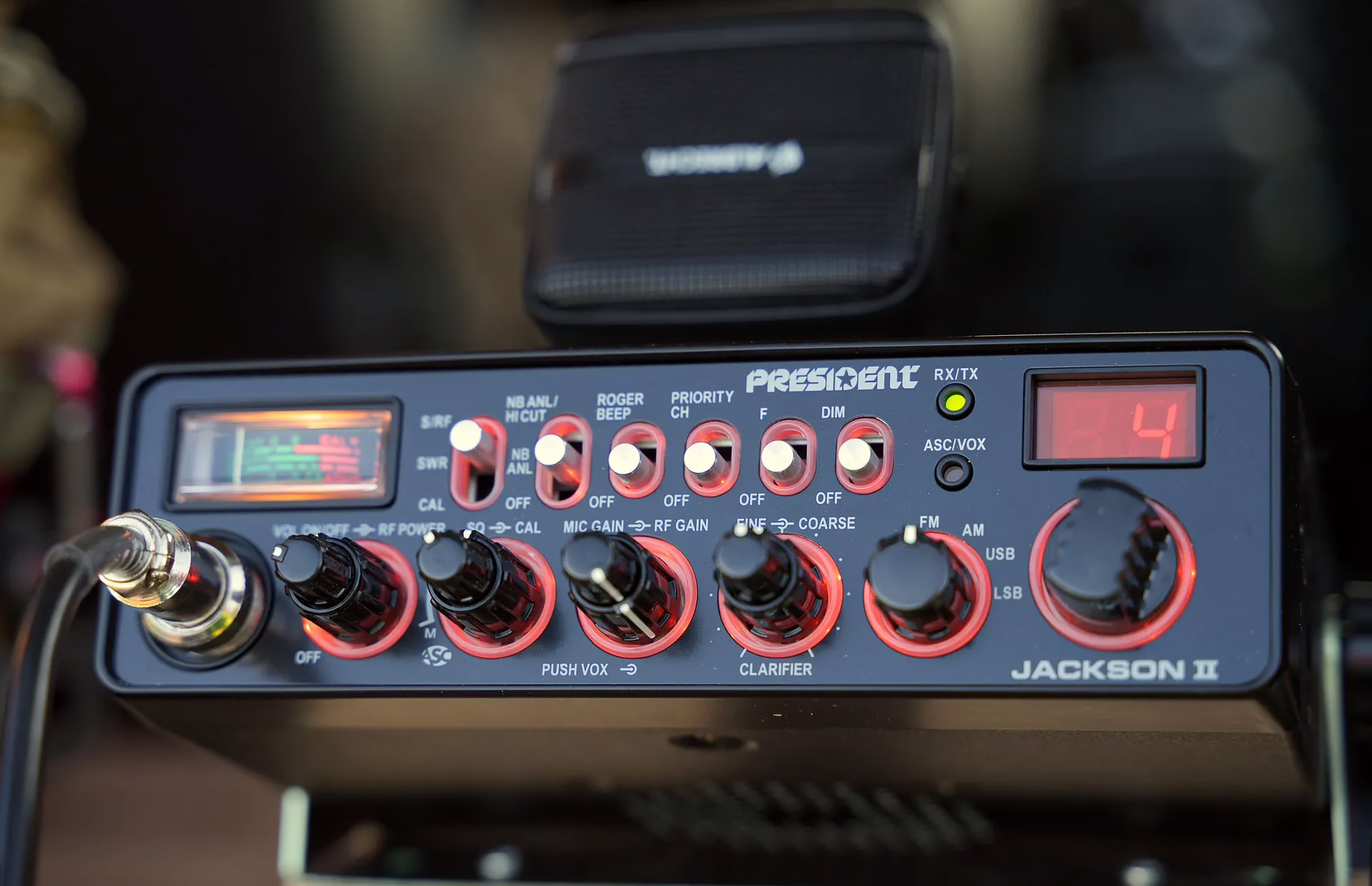 Close-up of a President Jackson II CB radio with illuminated controls, display screen, and microphone, ideal for radio communication content.